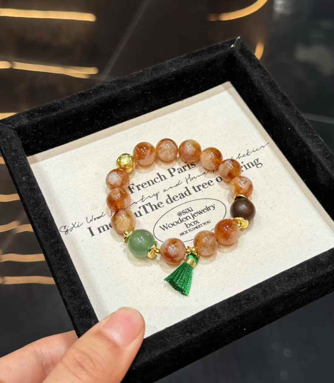 Detail of Agarwood bead, copper accents and green handmade tassel on gemstone bracelet
