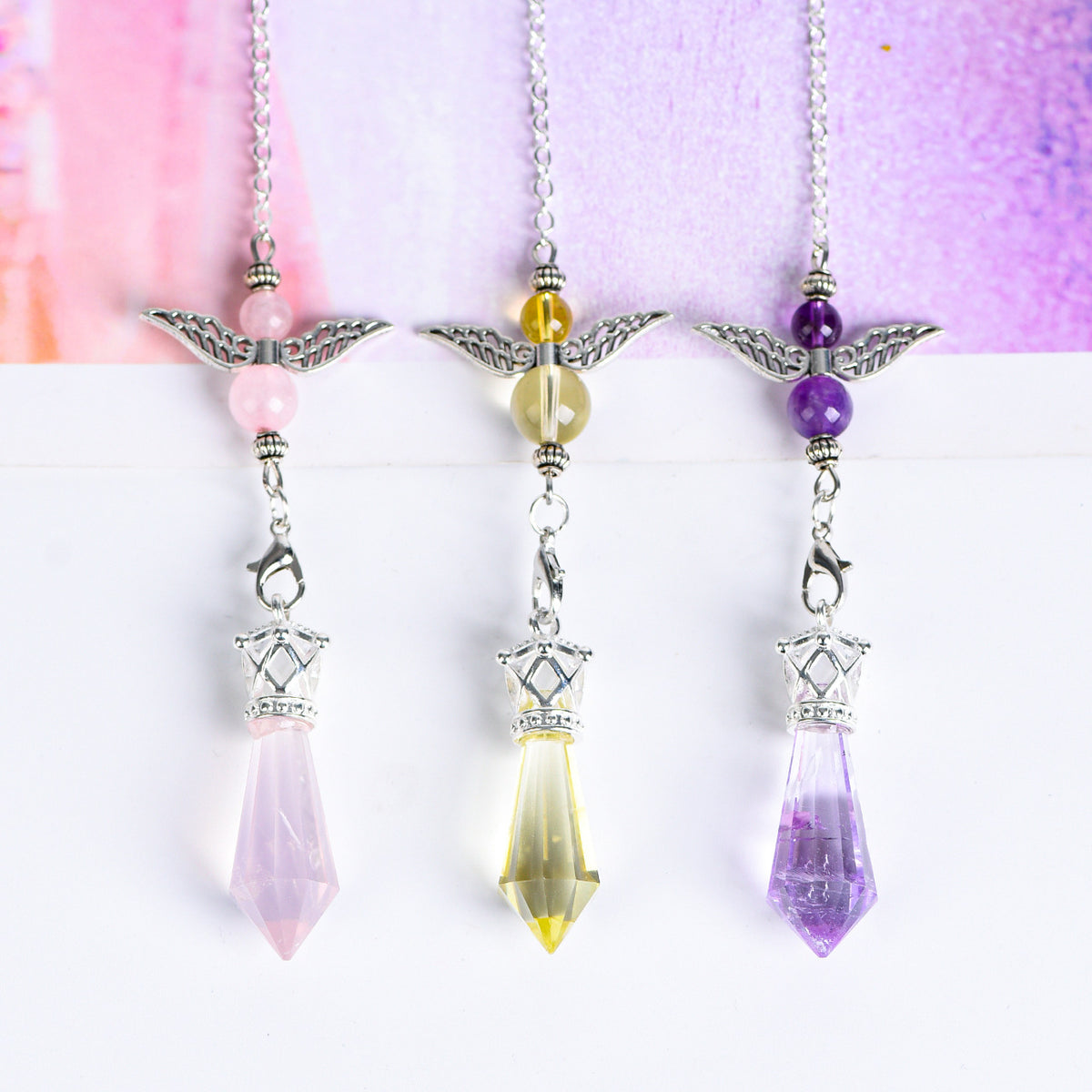 Full view of an Amethyst angel-wing pendulum with silver-tone link chain and faceted crystal point