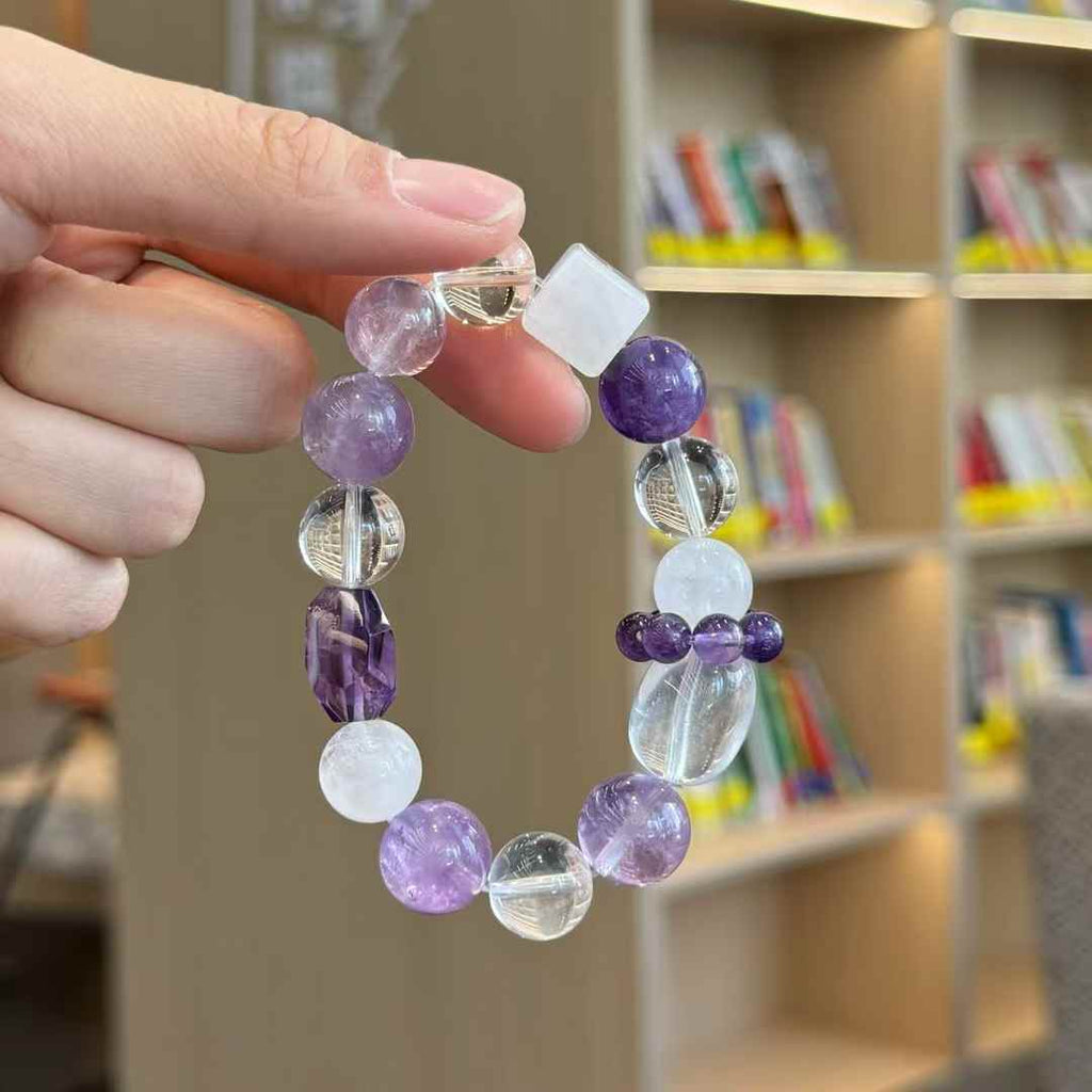 Mixed crystal bracelet detail showing a white cube bead, faceted purple focal bead and clear quartz accents
