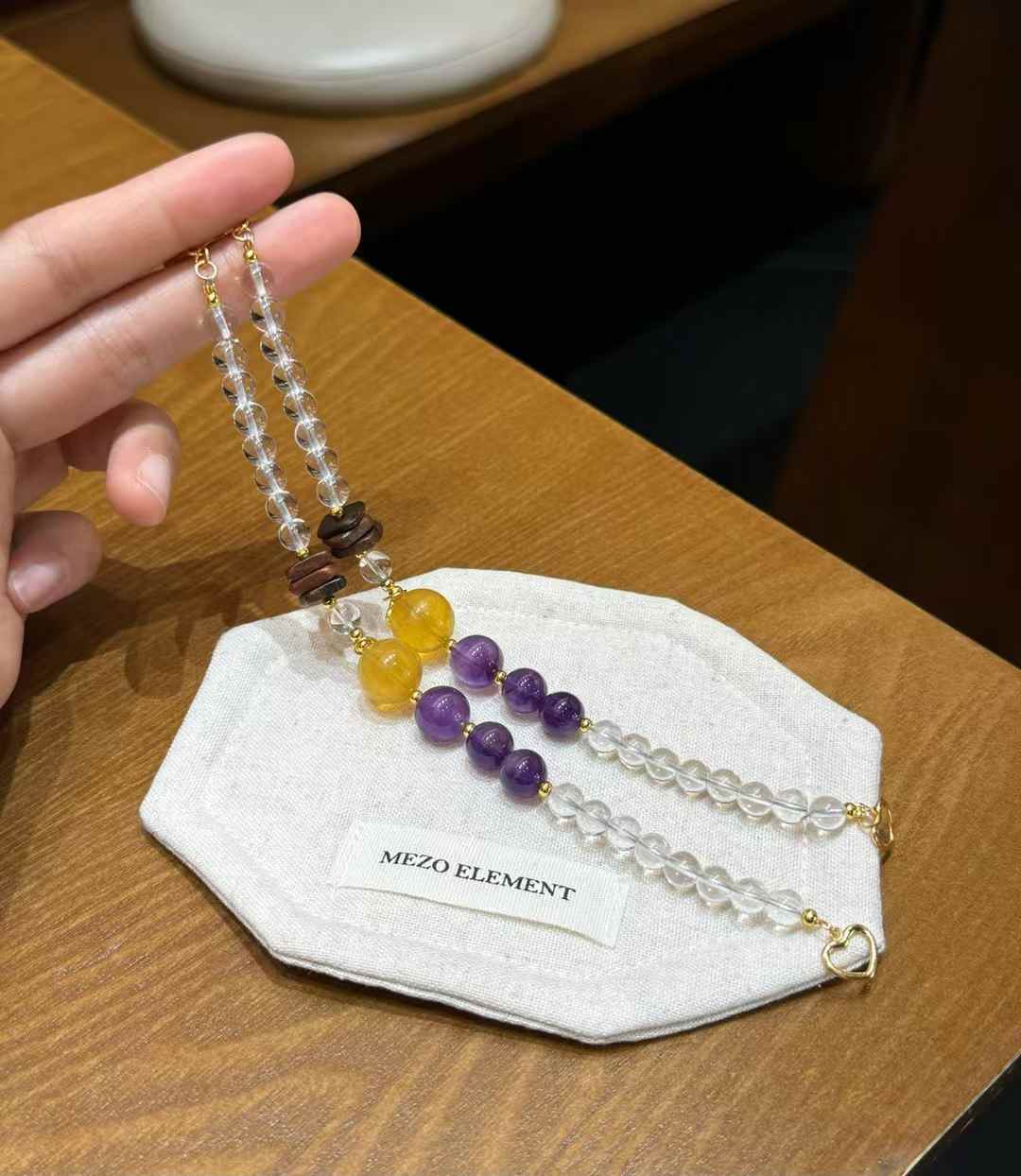 Handheld Clear Quartz bracelet showing graduated Amethyst and Yellow Fluorite bead sizes with Agarwood details
