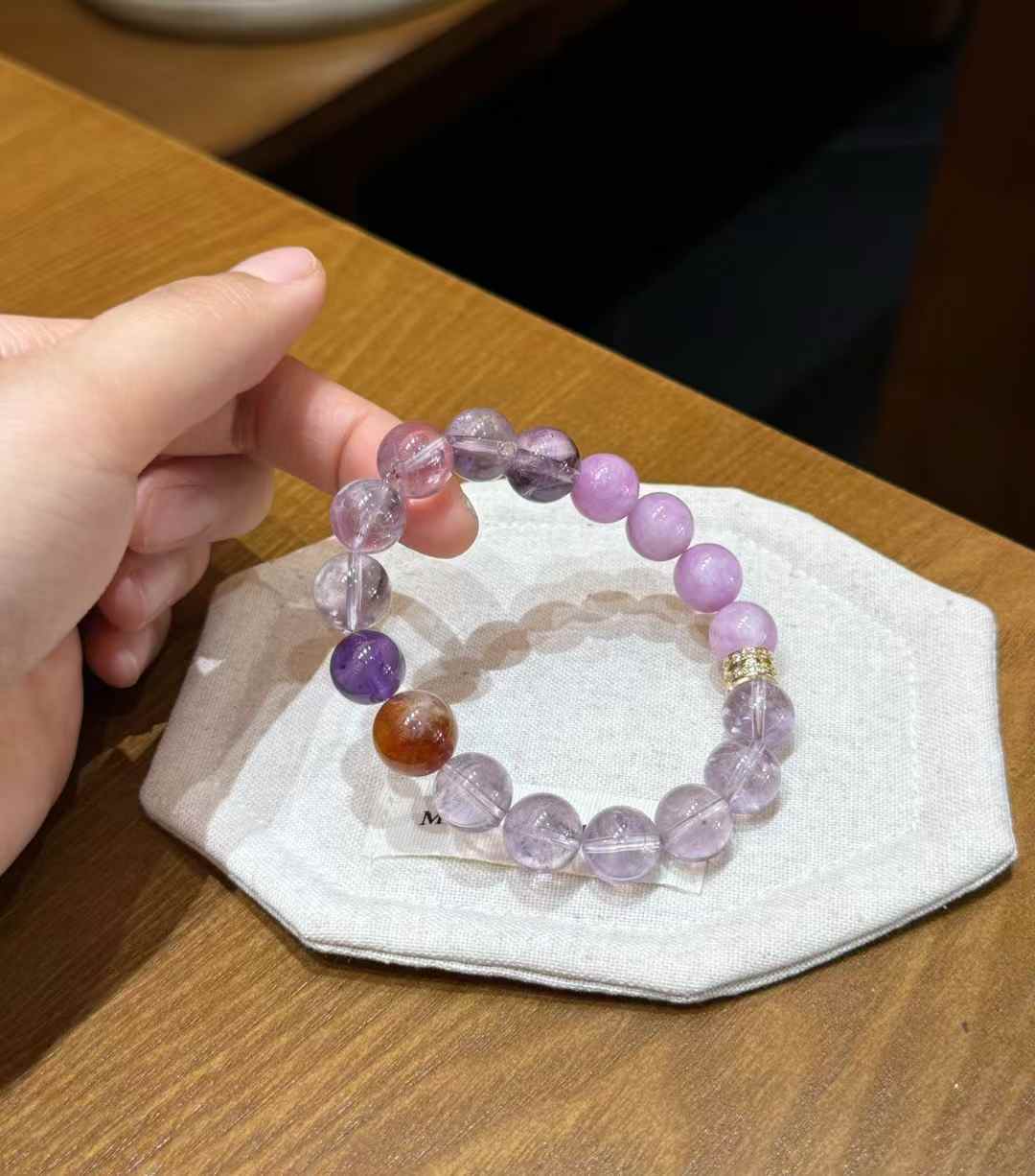 Handheld view of the mixed purple crystal bracelet with polished round beads and decorative spacer