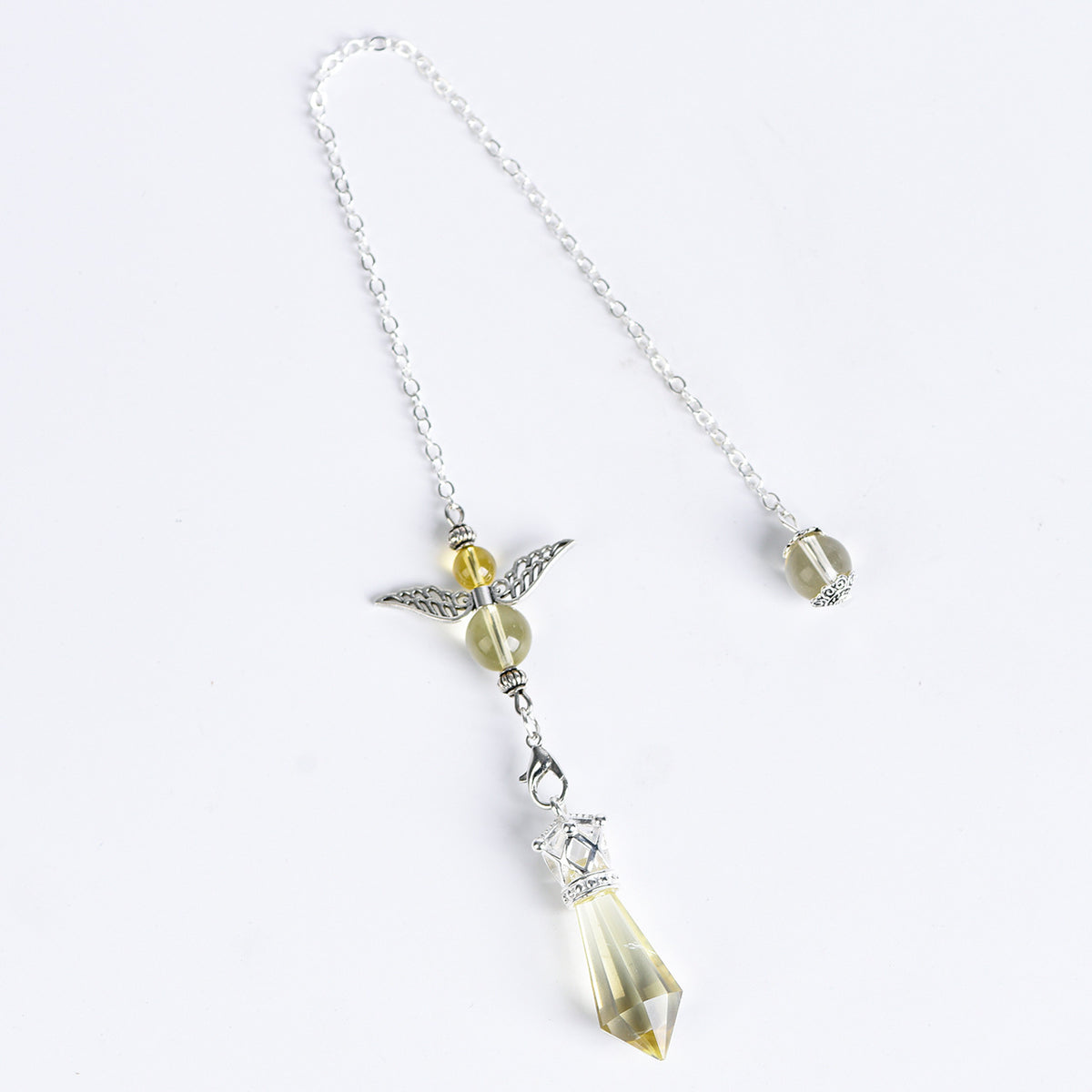 Faceted angel crystal pendulum displayed beside everyday objects to show overall scale