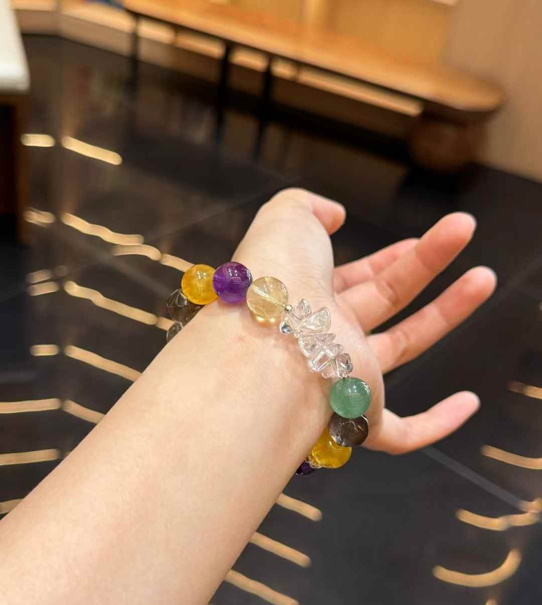 Autumn-toned mixed gemstone bracelet worn on the wrist with clear quartz and green gemstone accents