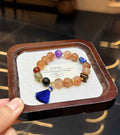 Veridia Black Gold Super Seven mixed gemstone bracelet with blue tassel displayed on a jewelry tray