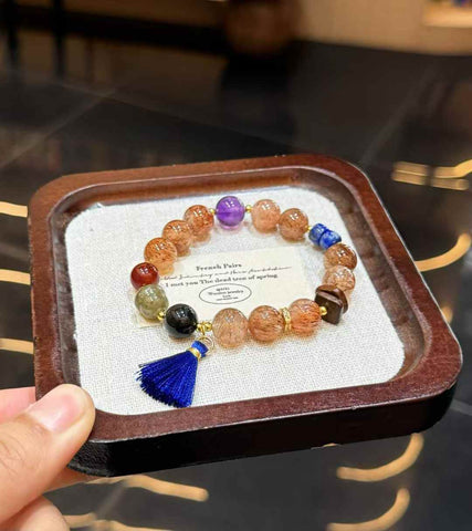 Veridia Black Gold Super Seven mixed gemstone bracelet with blue tassel displayed on a jewelry tray