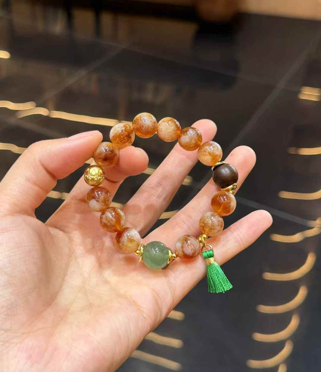 Chinese-inspired Yellow Tower Crystal bracelet worn on the wrist with green tassel and gemstone accents