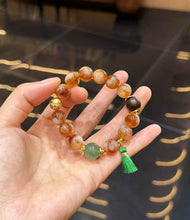 Chinese-inspired Yellow Tower Crystal bracelet worn on the wrist with green tassel and gemstone accents