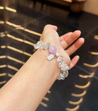 Clear Quartz and Kunzite gemstone bracelet worn on the wrist with silver-tone charm detail