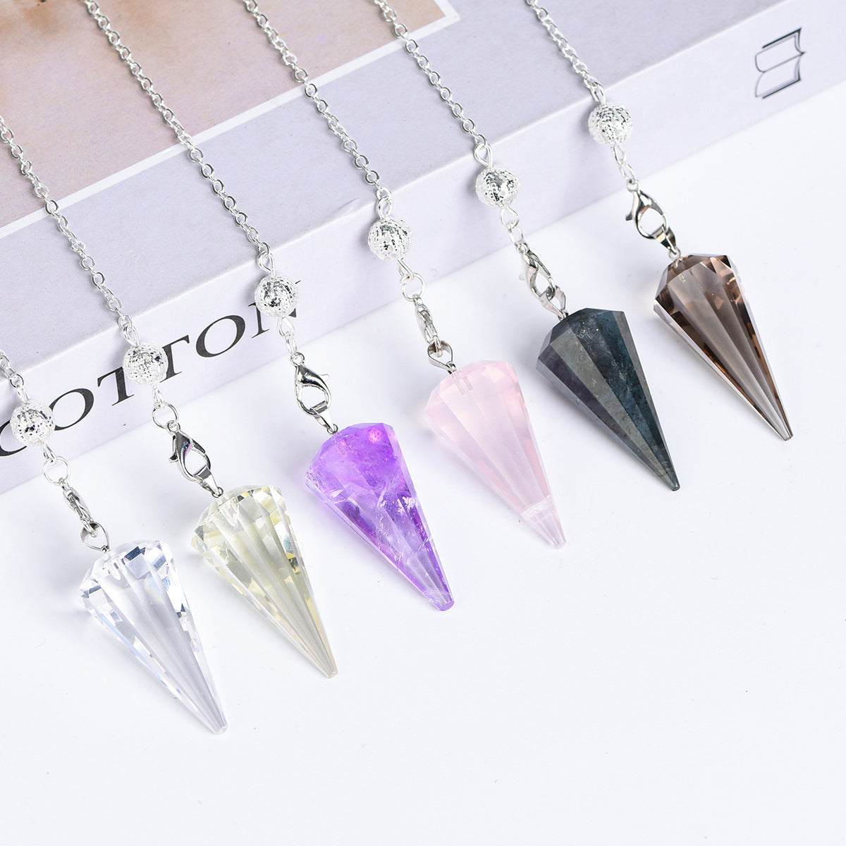 Clear Quartz 12-facet pointed crystal pendulum with silver-tone chain on a white background