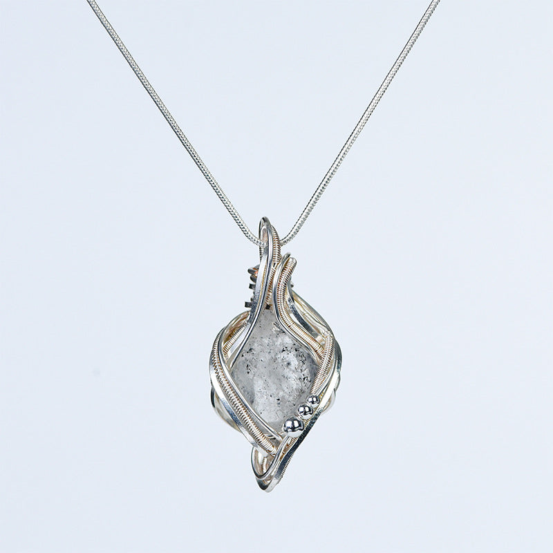 Sculptural crystal pendant necklace displayed with simple everyday objects to show its approximate scale