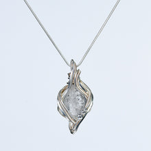 Sculptural crystal pendant necklace displayed with simple everyday objects to show its approximate scale