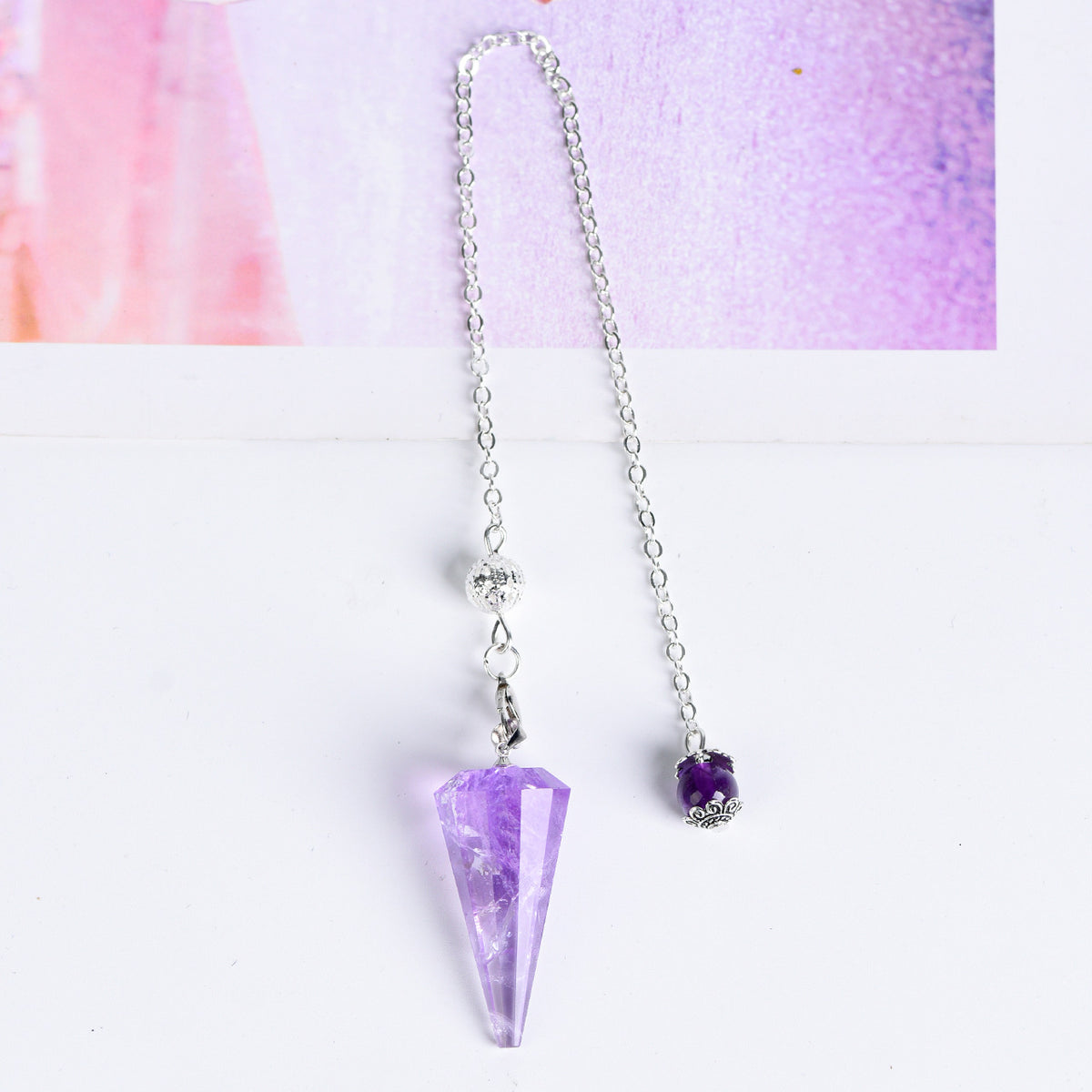 Close-up of the silver-tone chain, connecting clasp and faceted crystal pendulum hardware