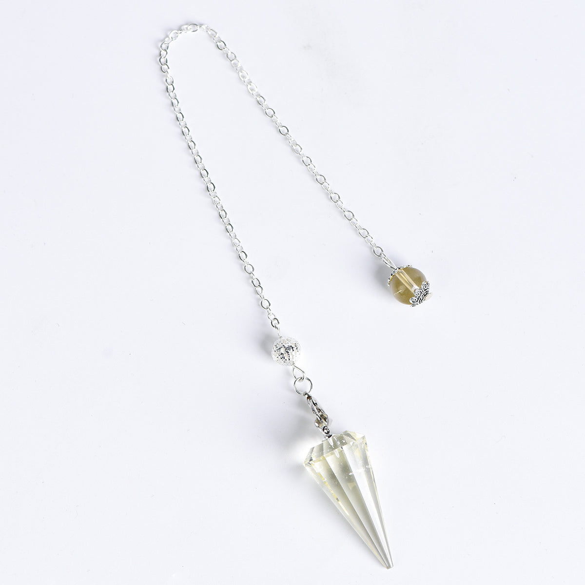Faceted crystal pendulum held by its chain during a simple personal ritual setting