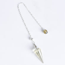 Faceted crystal pendulum held by its chain during a simple personal ritual setting