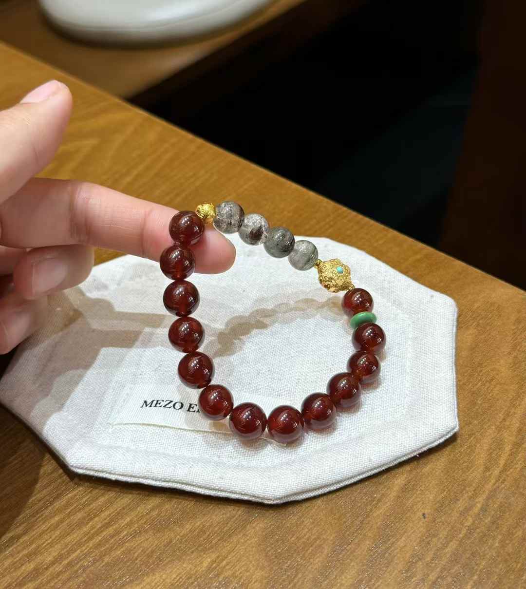 Garnet and Green Phantom Quartz bracelet showing the decorative gold-tone focal bead and green spacer detail