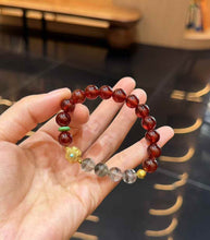 Close handheld view showing deep burgundy Garnet beads and translucent Green Phantom Quartz inclusions