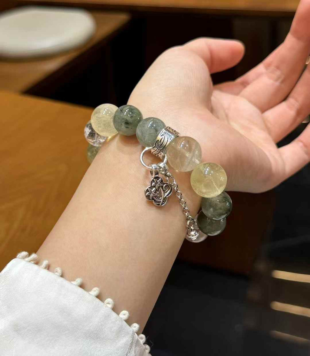 Two Green Rutilated Quartz and Lemon Quartz bracelets displayed together on a soft jewelry tray