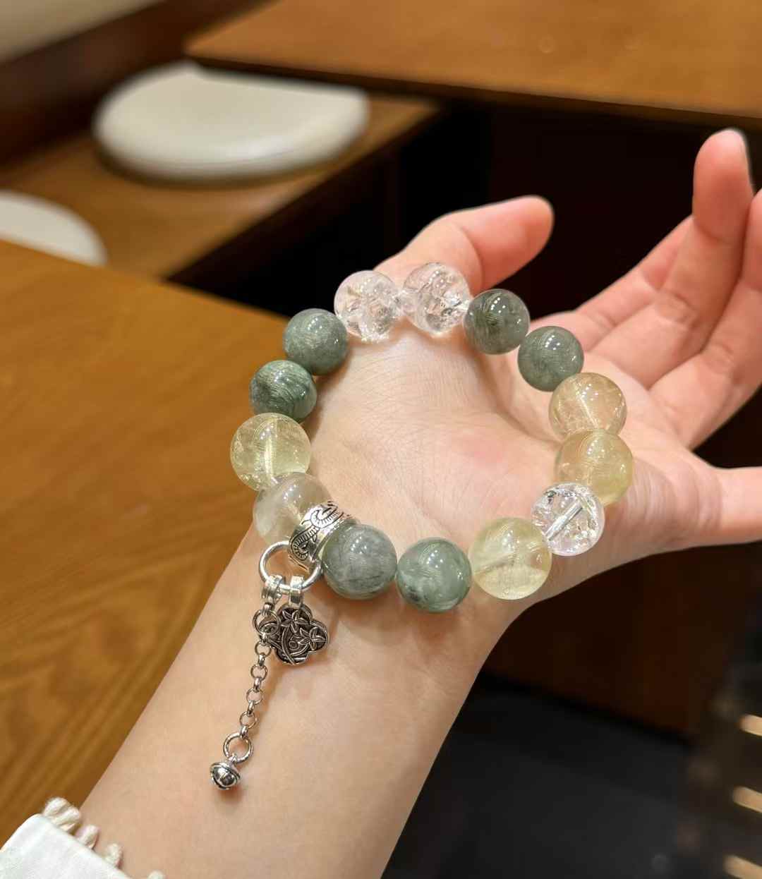 Full view of the mixed-crystal bracelet showing green, pale yellow and clear round beads with Tibetan-silver-tone alloy accents