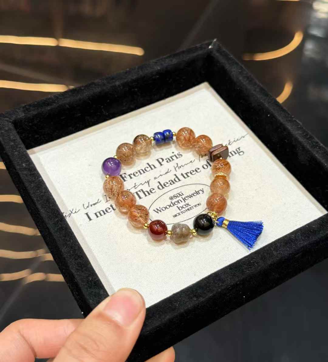 Mixed gemstone bracelet showing gold-tone spacers, dark blue tassel and contrasting gemstone arrangement