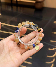 Handheld mixed gemstone bracelet showing the scale and arrangement of Yellow Tower Quartz, Tiger Eye and dark wood accents