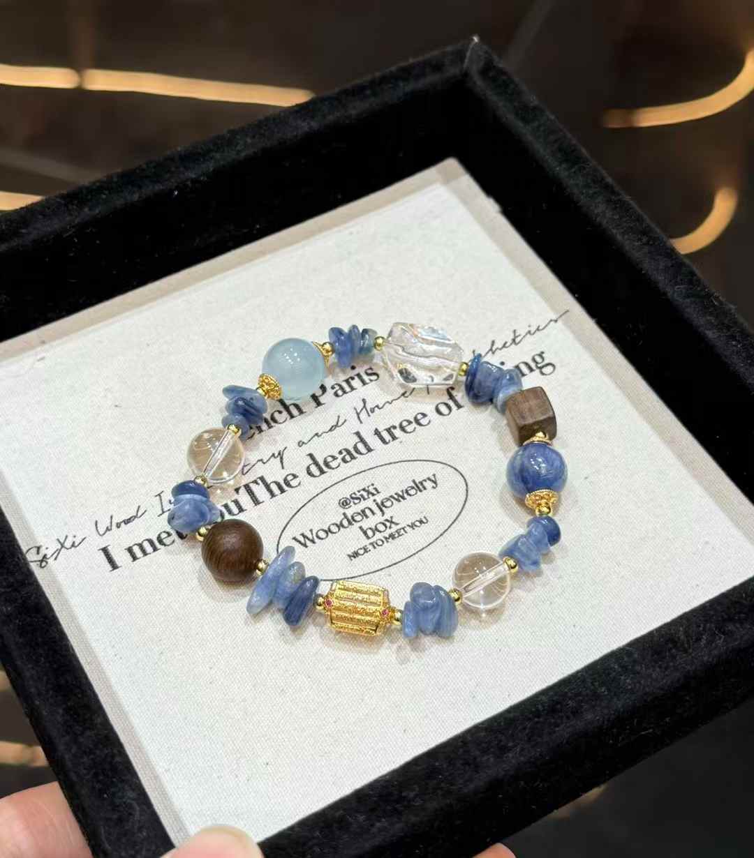 Veridia ocean-inspired bracelet with Blue Crystal, Aquamarine, Clear Quartz, wood accents and gold-tone details displayed on a jewelry tray