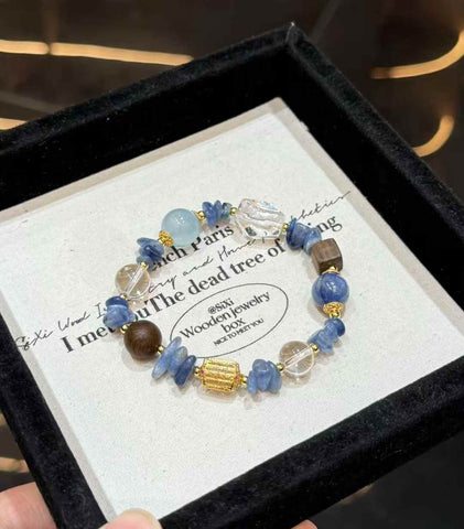 Veridia ocean-inspired bracelet with Blue Crystal, Aquamarine, Clear Quartz, wood accents and gold-tone details displayed on a jewelry tray