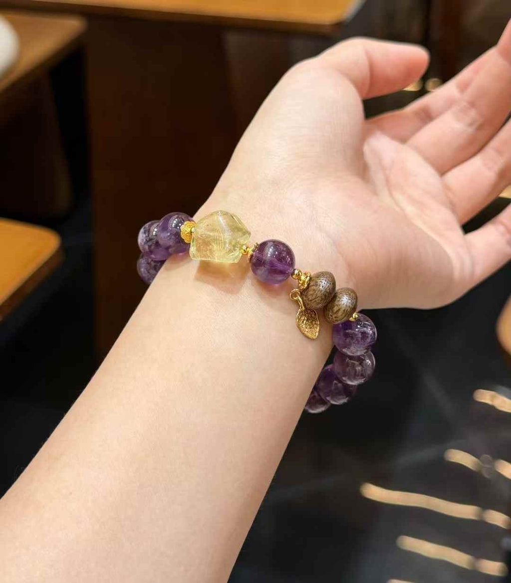 Purple Rabbit Hair Quartz and Citrine bracelet worn on the wrist with Agarwood accents and gold-tone charm