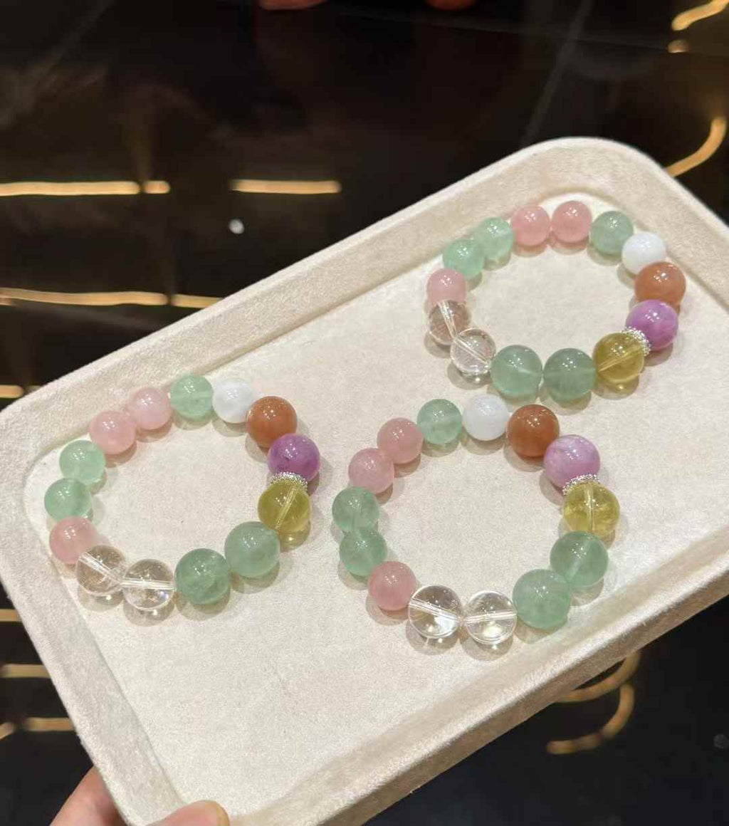 Three rainbow multi-gemstone bead bracelets displayed together on a soft jewelry tray