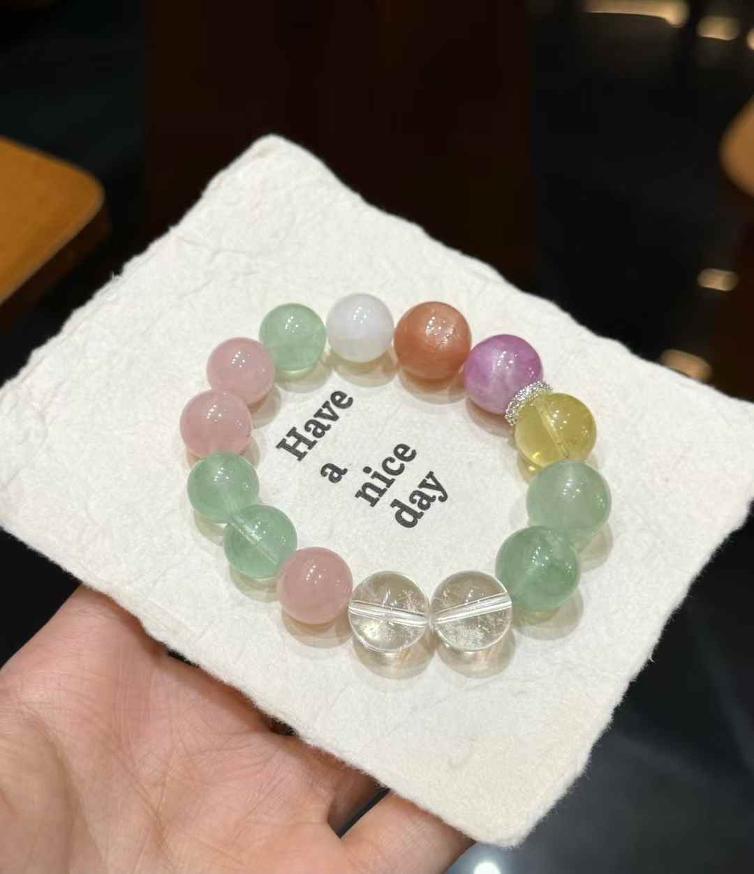 Veridia rainbow multi-gemstone bracelet held in hand with Clear Quartz, Green Fluorite, pink, purple and golden gemstone beads