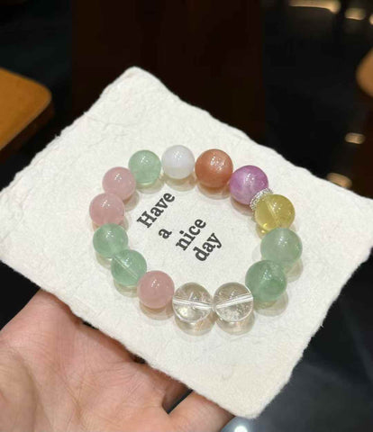 Veridia rainbow multi-gemstone bracelet held in hand with Clear Quartz, Green Fluorite, pink, purple and golden gemstone beads