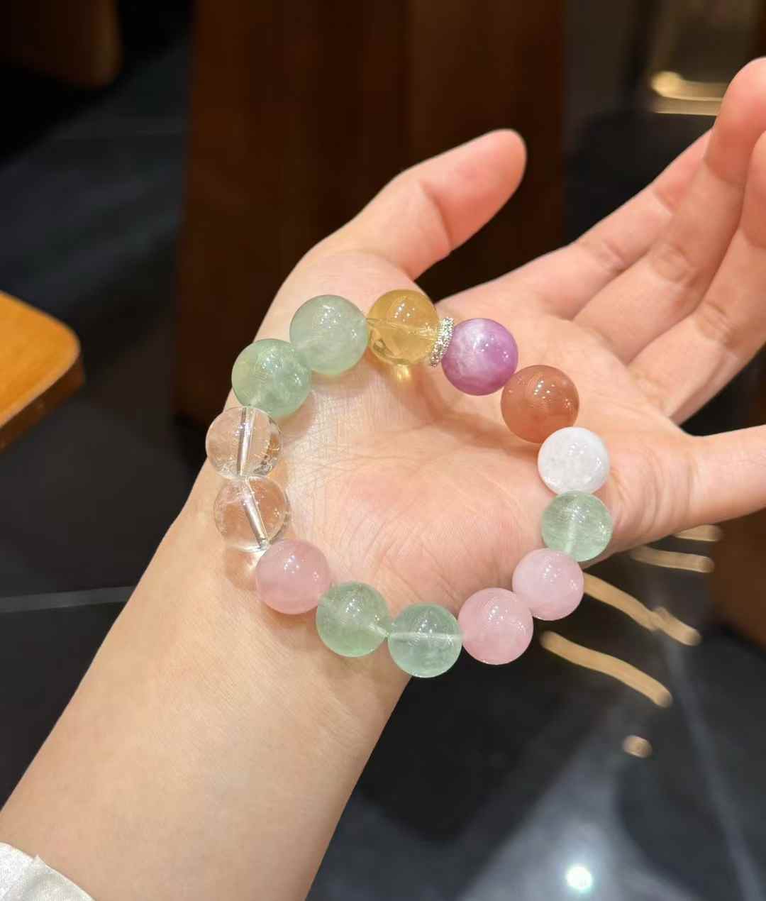 Rainbow multi-gemstone bead bracelet arranged on soft white fabric in a casual lifestyle setting
