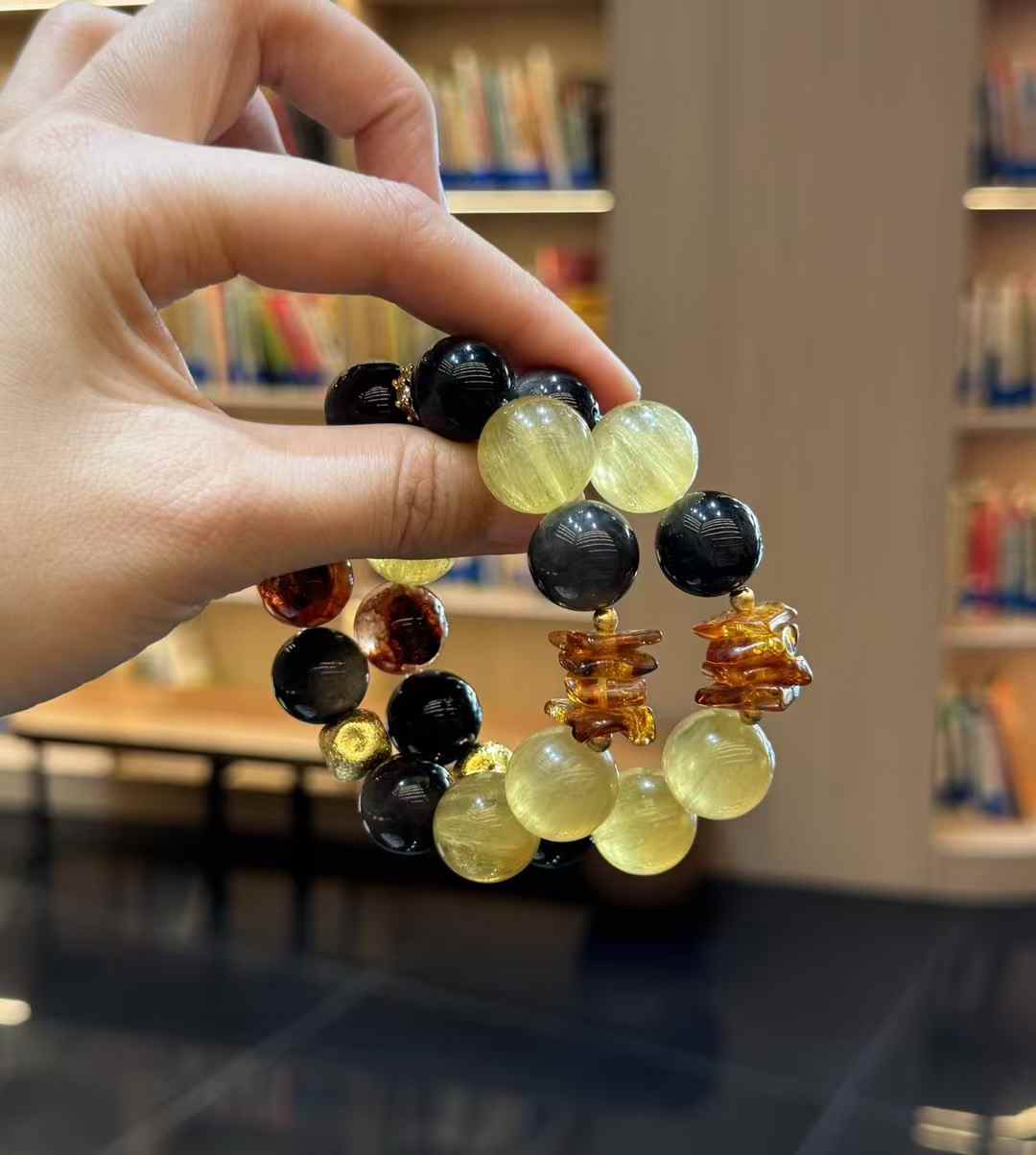 Handheld bracelet showing Red Hematoid Quartz, amber spacer elements, Yellow Fluorite and dark obsidian beads