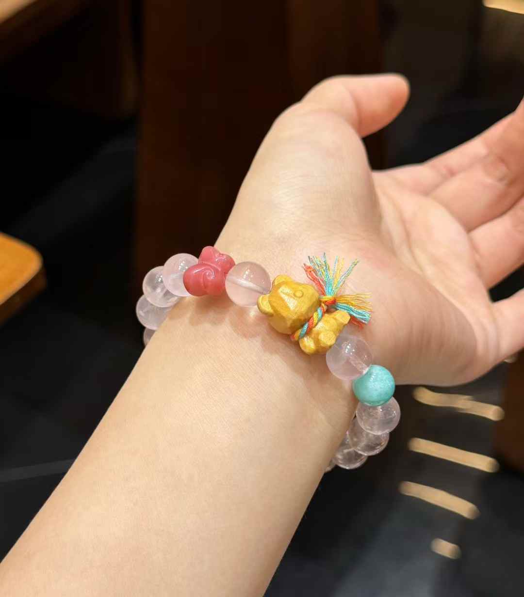 Rose Quartz bracelet detail featuring a carved wooden bear charm with multicolor cord accent