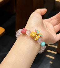 Rose Quartz bracelet detail featuring a carved wooden bear charm with multicolor cord accent