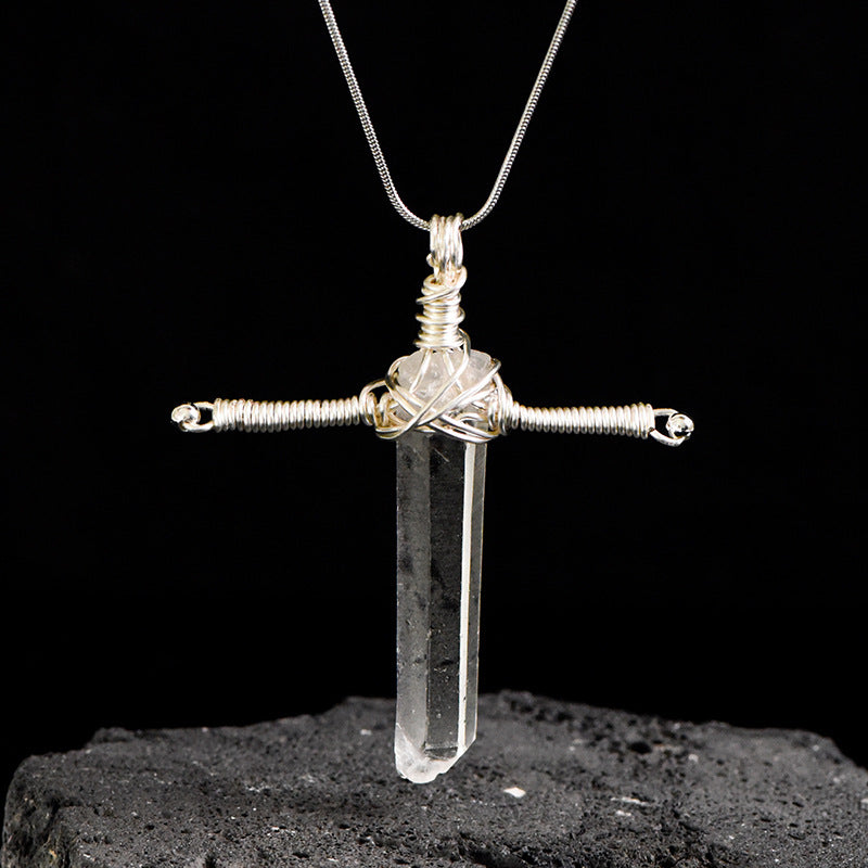 Close-up of silver-tone wire wrapping around a Clear Quartz pendant with geometric metal detailing