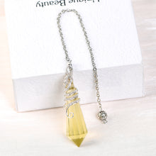 Golden-tone faceted crystal pendulum displayed beside a white box in a clean lifestyle setting