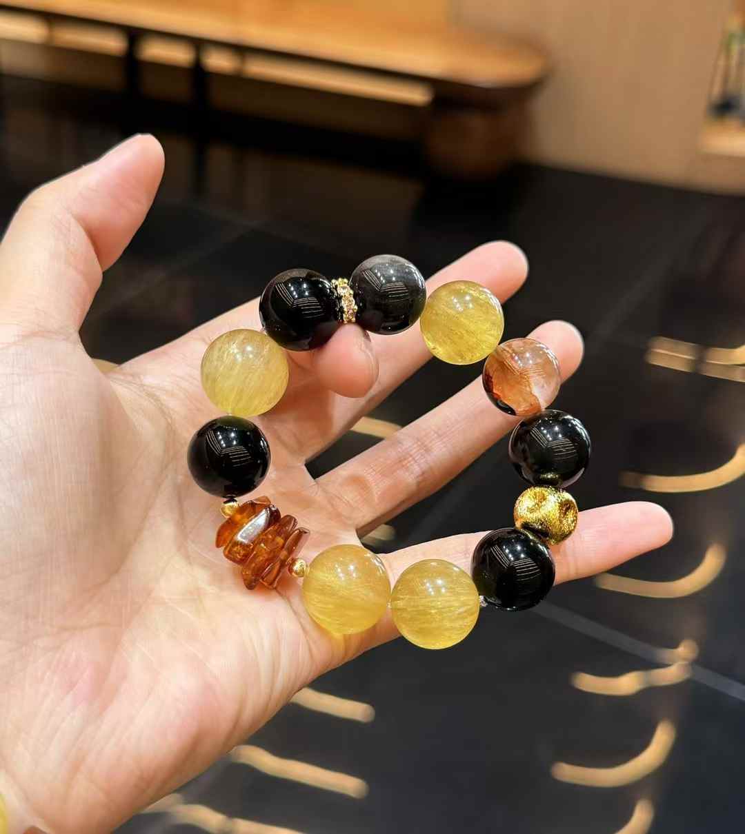 Close view of polished Yellow Fluorite and glossy Silver Sheen Obsidian beads in an oversized bracelet