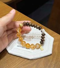Handheld Yellow Hematoid Quartz and Agarwood bracelet showing the contrast between golden crystal and dark wood beads